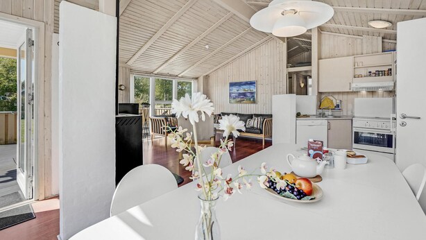 A modern kitchen with white cabinets, a dining area with a white table, and a view of the outdoors. - Stunning home in Sydals with sauna (Sydals)