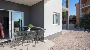 Un pati exterior modern amb taula i cadires, una planta en test i vista a una zona residencial.