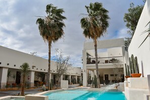 A pool area with palm trees, a white building, and a water feature. - Hotel Plaza Cuatrociénegas (Cuatro Ciénegas)