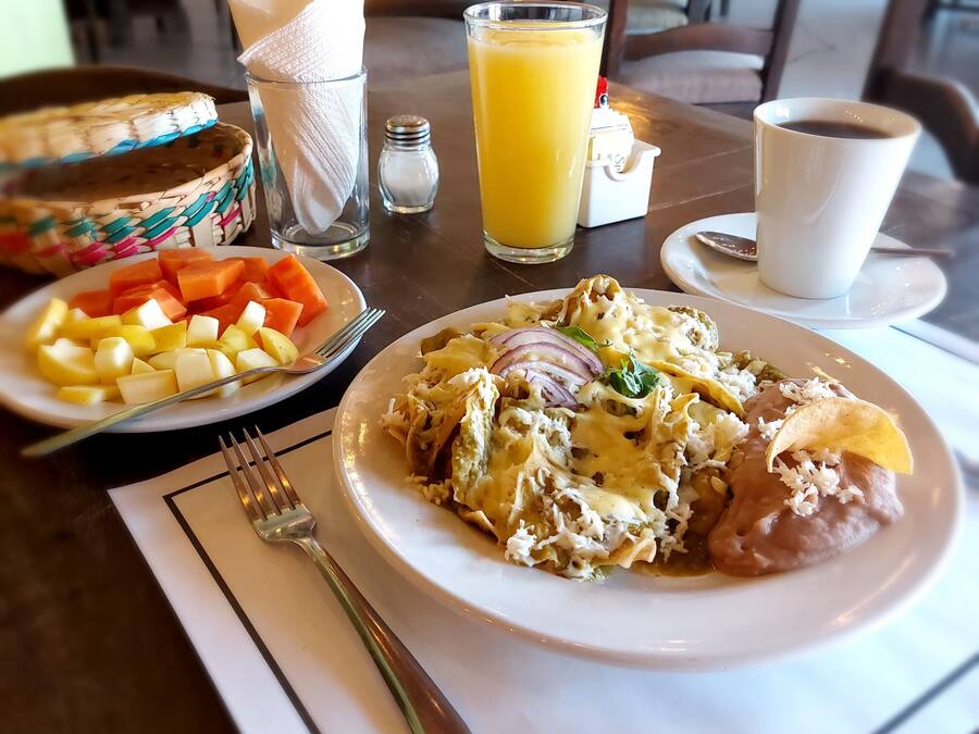 A dining table with a plate of food, a glass of orange juice, a cup of coffee, and a napkin.