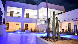 A modern hotel with a pool area, multiple balconies, and a well-lit entrance.