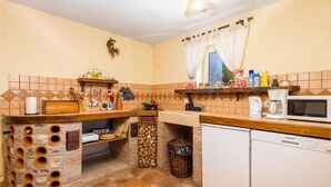 A kitchen with a brick oven, wooden shelves, a microwave, and a coffee maker.