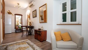 Un soggiorno con un divano, un'area pranzo con tavolo e sedie, un mobiletto in legno e un grande specchio a parete.