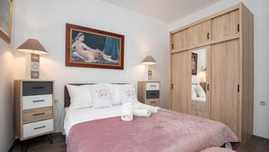 Une chambre à coucher avec un lit, une armoire, une table de chevet et un tableau au mur.