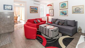 Un salon moderne avec un ensemble de canapés rouge et gris, une table basse et un tapis à motifs.