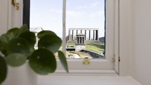 A window view of a classical building with columns, a lock on the window, and a plant in the foreground. - Observatory House & Apartment (Edinburgh)
