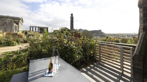 A terrace with a table set for a meal, overlooking a historic building and a tower. - Observatory House & Apartment (Edinburgh)