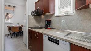 Una cocina compacta con lavavajillas, cafetera y armarios de madera.