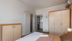 Una habitación de hotel con cama, armario, baño y un pasillo.
