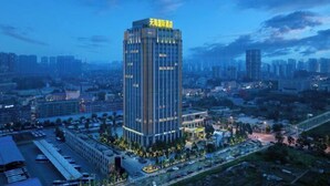 A modern high-rise hotel with a prominent vertical design, surrounded by a well-lit urban area with visible roads and other buildings. - Tianhai International Hotel (Changsha Gaoxin District Meixi Lake park) (Changsha)