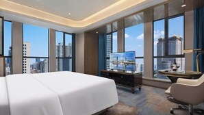 A modern hotel room with a large bed, a desk with a flat-screen TV, and a city view through large windows. - Tianhai International Hotel (Changsha Gaoxin District Meixi Lake park) (Changsha)