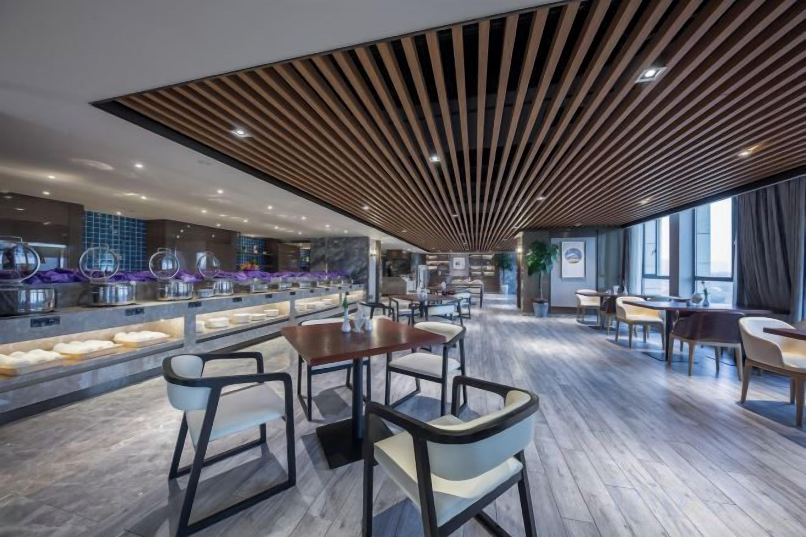 Interior moderno de restaurante com teto de madeira, piso de mármore e um balcão longo com displays de comida.