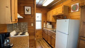 Cocina compacta con armarios de madera, estufa, refrigerador y microondas.