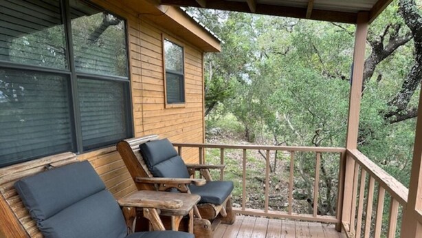 Terraza de madera con dos sillones y una mesita.