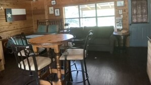 A wooden interior with a round table and chairs, a sofa, and a ceiling fan. - Relaxing Getaway at The Siesta Cabin, Pet Friendly (Fredericksburg)