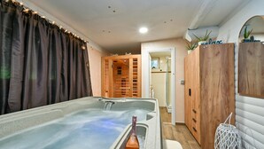 Un cuarto de spa con hidromasaje, armarios de madera y un espejo.