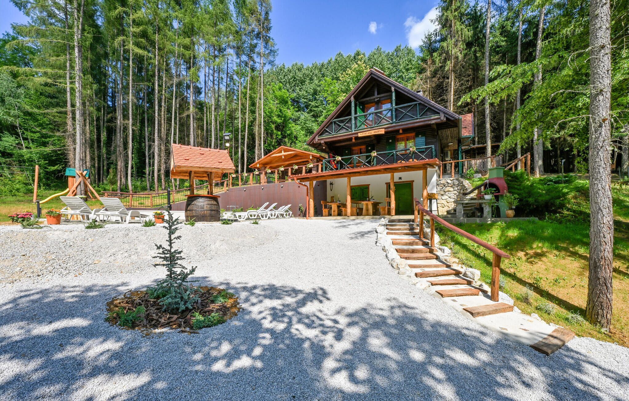 A lodge with a wooden staircase leading to a covered porch, surrounded by a forest.