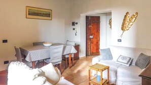 A dining area with a table and chairs, a sofa, and a door leading to another room.