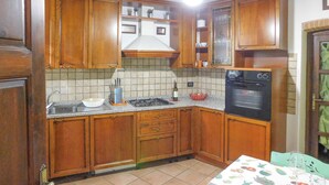 A kitchen with wooden cabinets, a gas stove, a sink, and an oven.