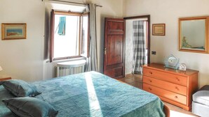 A bedroom with a bed, dresser, and a window with curtains.