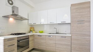 Una cocina moderna con armarios blancos, una campana de acero inoxidable, una estufa a gas, un horno empotrado y un lavamanos con grifo.