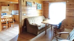 L’intérieur chaleureux d’un chalet, avec un revêtement mural en bois, un canapé, une table à manger et des chaises.
