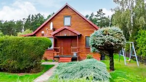 Une maison en bois avec un toit rouge, une porte d’entrée et une petite fenêtre.