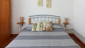 Un letto con biancheria a righe, due lampade a parete e due opere d'arte appese al muro.