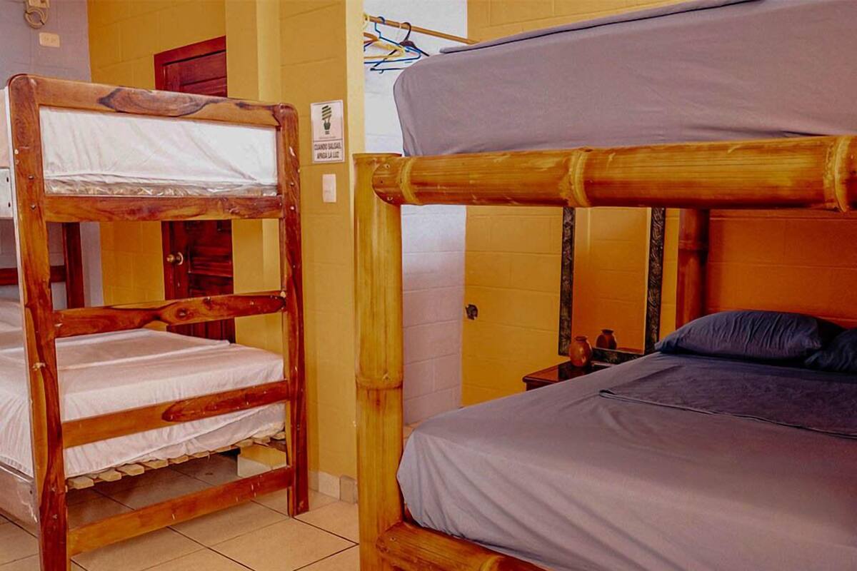 Une chambre avec deux lits superposés, l’un avec une structure en bois et l’autre avec une structure en bambou.