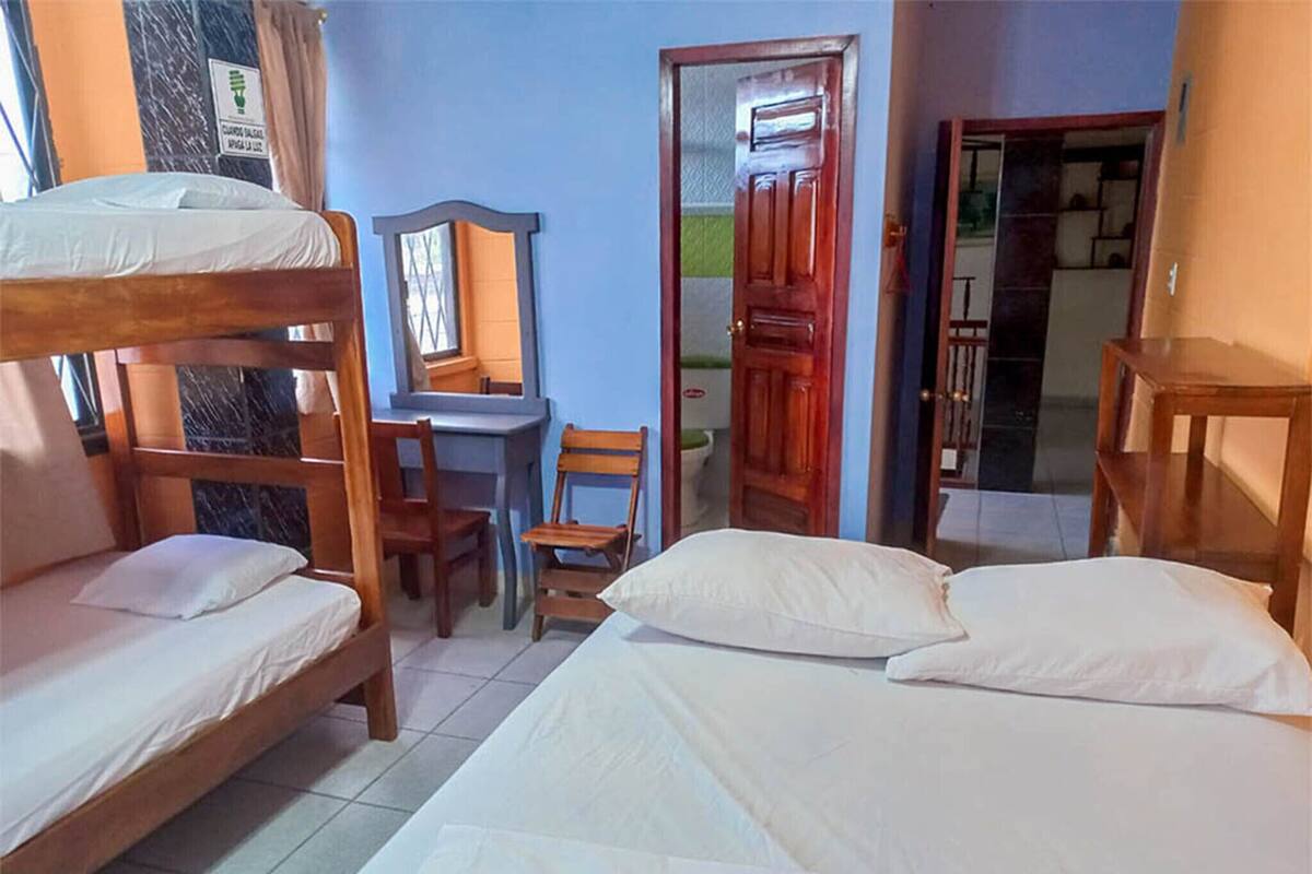 Une chambre de dortoir avec des lits superposés, un bureau, une chaise et un miroir.