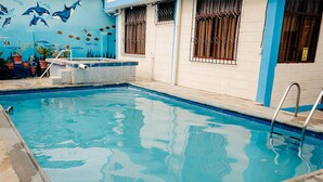Una piscina con borde de azulejos, una escalera y un mural de vida marina en la pared contigua.