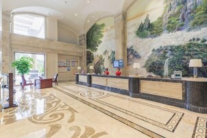 Un vestíbulo de hotel con mostrador de recepción, zona de estar y un mural grande.