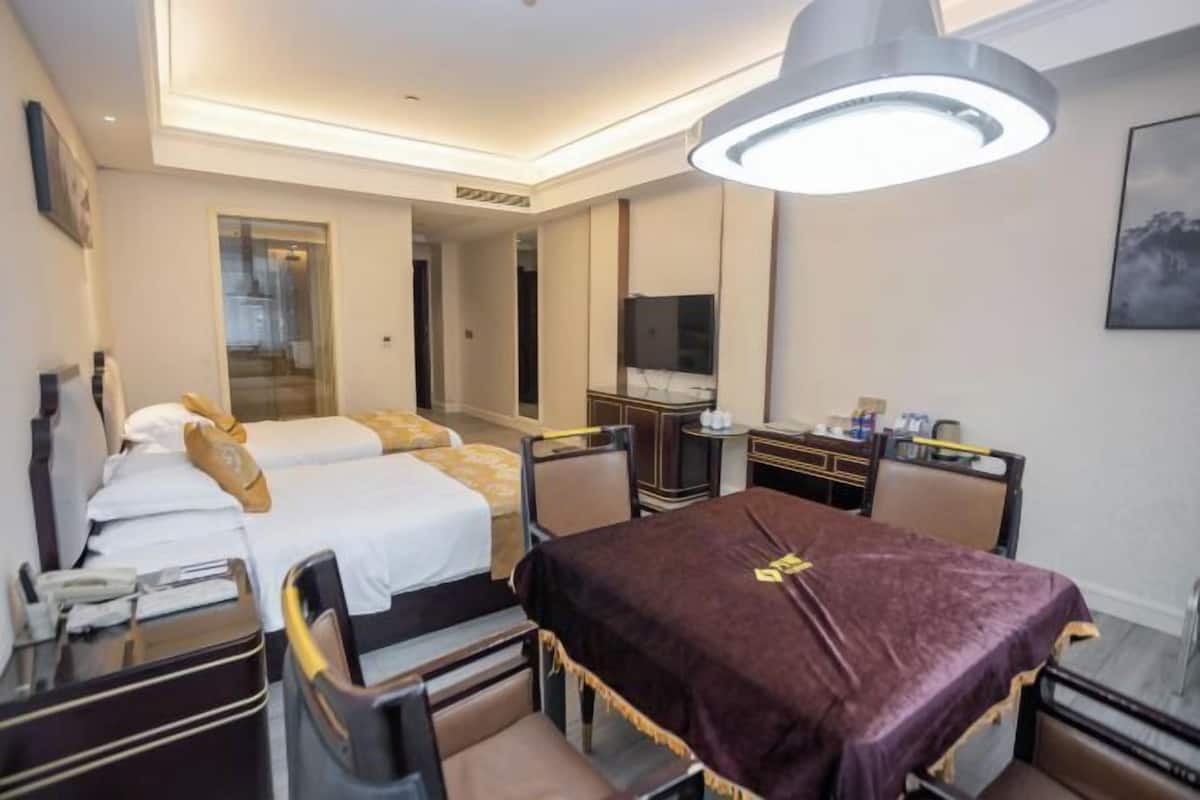A hotel room with a bed, a desk, a chair, a table, a mirror, and a television.