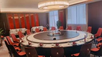 A conference room with a round table, red chairs, and a modern chandelier.