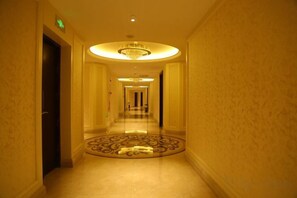A hotel hallway with a circular patterned floor, a chandelier, and a door on the left. - Anfu Jiangjing Hotel (Anfu)