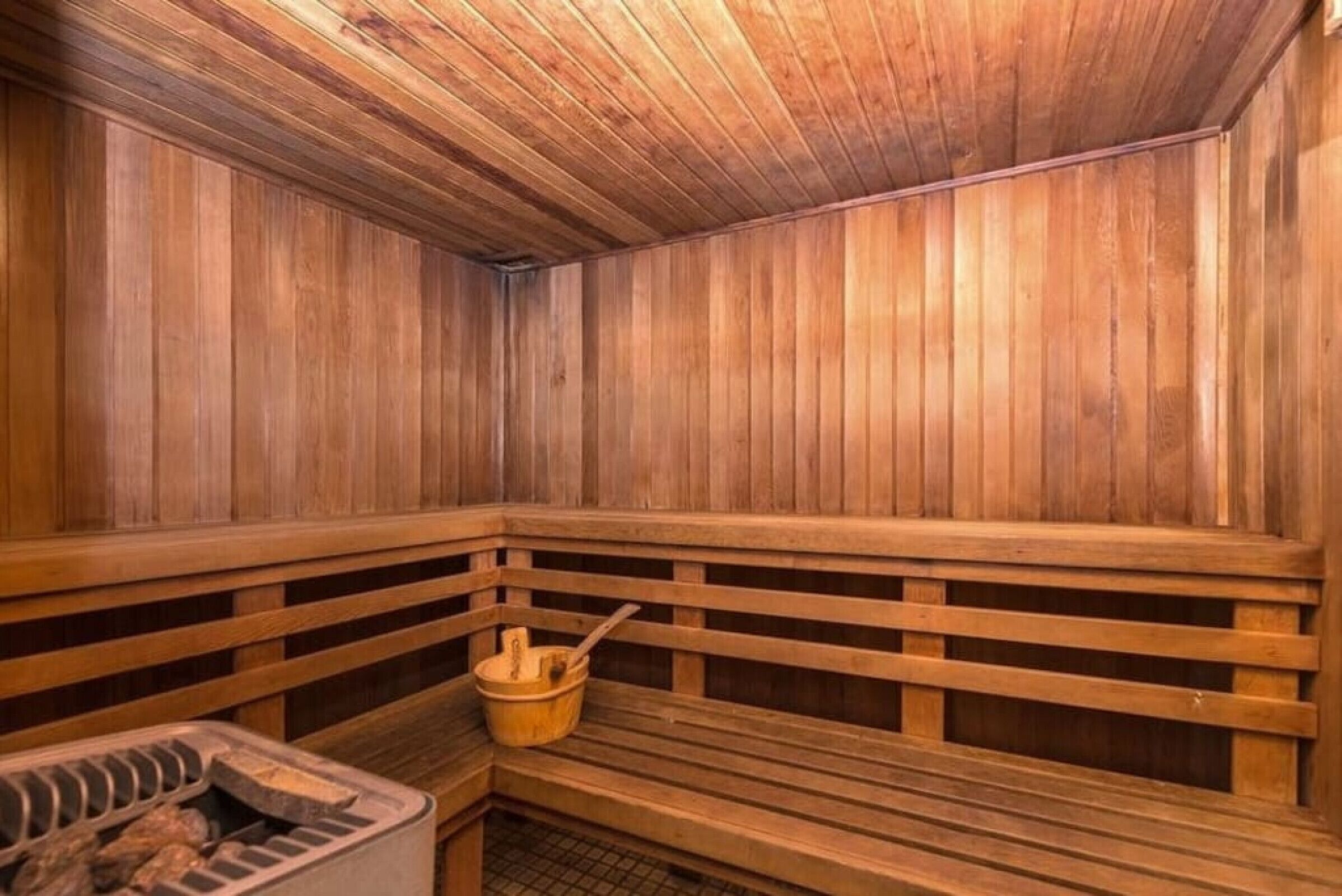 A sauna with wooden benches and a wooden bucket.
