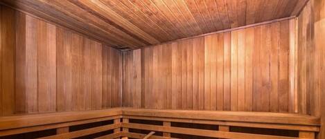 A sauna with wooden benches and a wooden bucket.