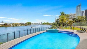 En swimmingpool med utsikt över en flod och stadens silhuett.