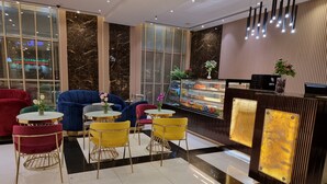 Un intérieur moderne avec un espace salon comprenant des canapés rouges et bleus, des chaises jaunes et un mur en marbre.