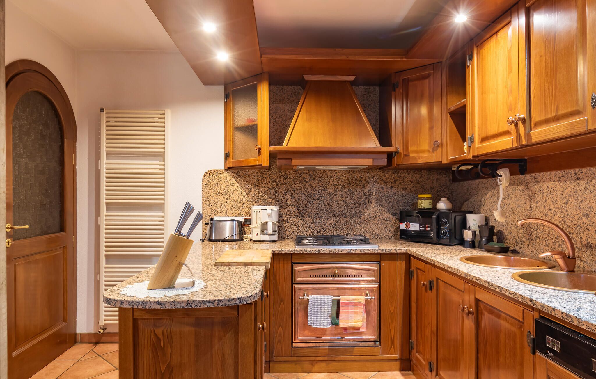 A kitchen with wooden cabinets, a stove, a coffee maker, and a sink.
