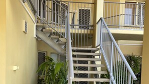 A multi-level building with a central staircase, metal railings, and air conditioning units. - Perfect little home away from home in the tropics. (Parap)