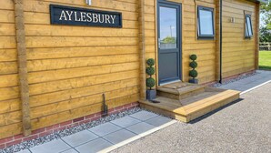 A wooden building with a sign reading "AYLESBURY" and a door with a small porch. - Indulge and delight at this wonderful lodge, with your own private hot tub. (Halstead)