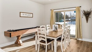 A dining area with a wooden table and chairs, a foosball table, and a 'be our guest' sign on the wall. - Modern Red Lodge Cabin - Walk to Broadway Ave (Red Lodge)
