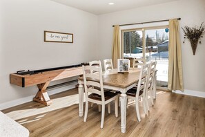 A dining area with a wooden table and chairs, a foosball table, and a 'be our guest' sign on the wall. - Modern Red Lodge Cabin - Walk to Broadway Ave (Red Lodge)