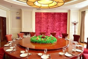 A round dining table with chairs, a floral centerpiece, and a red velvet wall in the background. - Jinduhui International Hotel (Guiyang Ouyanghai Plaza) (Guiyang)