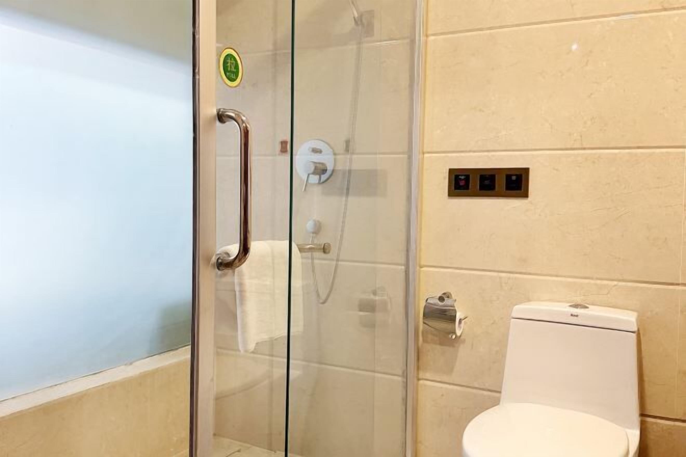 A bathroom with a glass shower enclosure, a white toilet, and a towel rack.