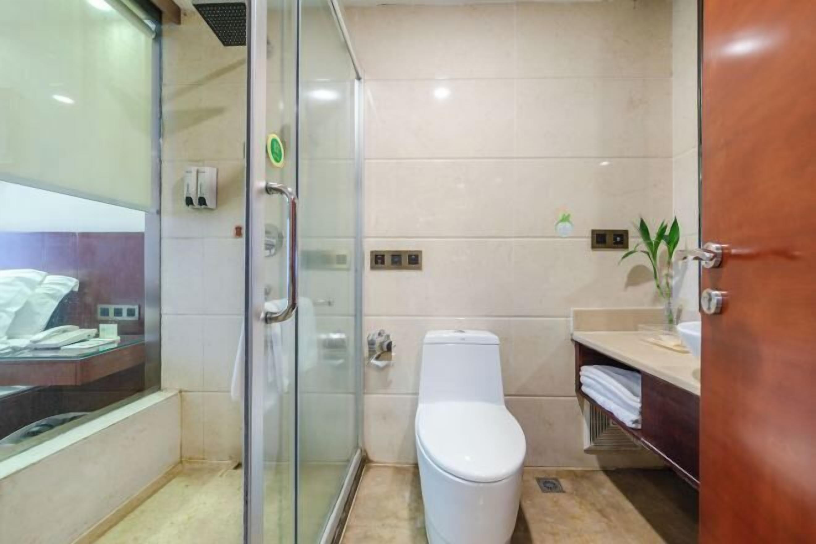 A modern bathroom with a glass shower enclosure, a white toilet, and a vanity with a sink and towel rack.