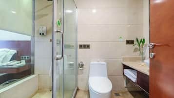 A modern bathroom with a glass shower enclosure, a white toilet, and a vanity with a sink and towel rack.