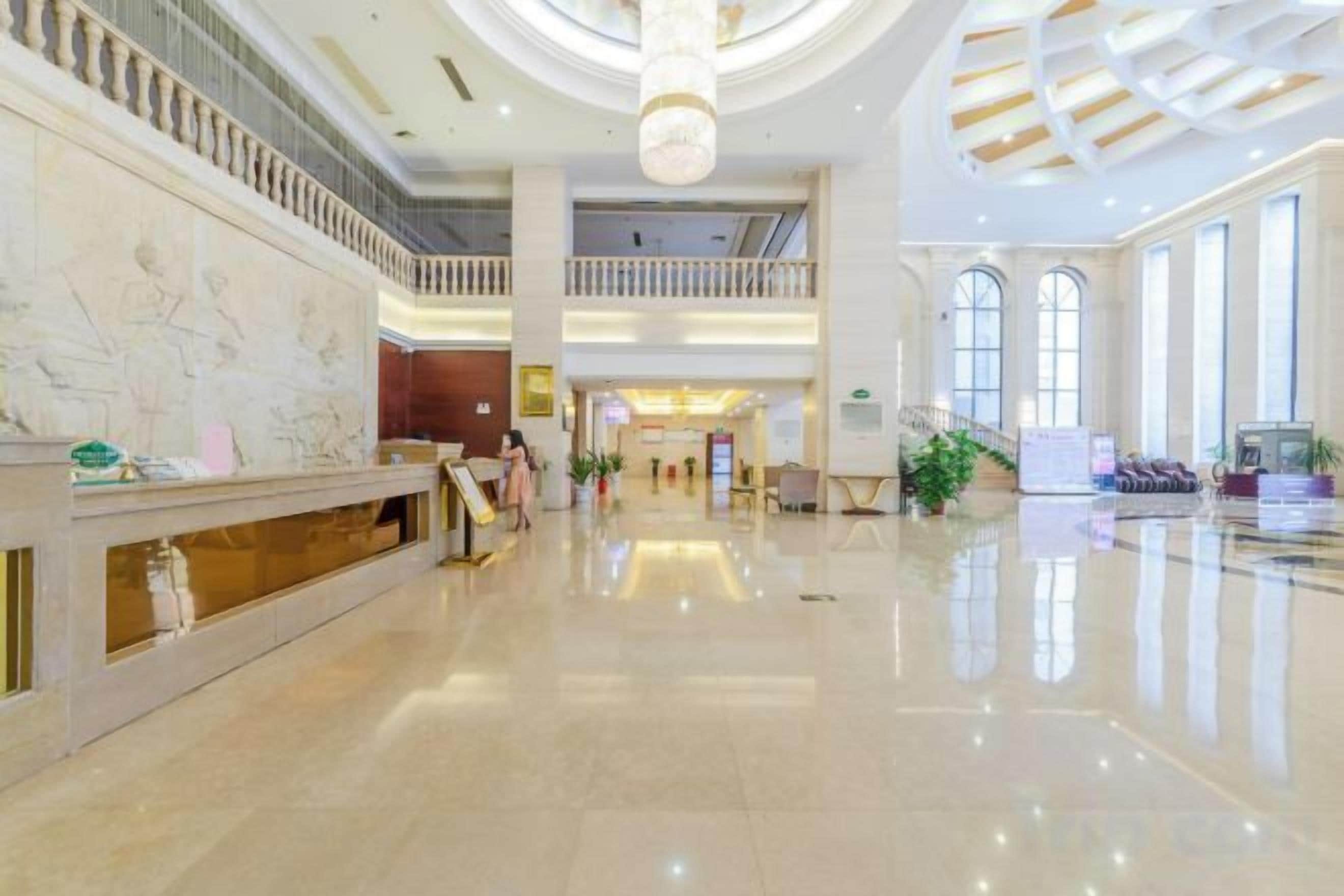 A spacious lobby with a reception desk, a staircase, and a high ceiling with a circular skylight.