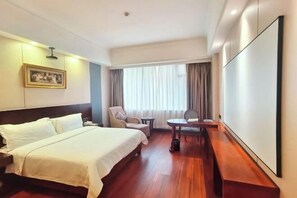 Una habitación de hotel con una cama, una silla, una mesita y un ventanal grande con cortinas.